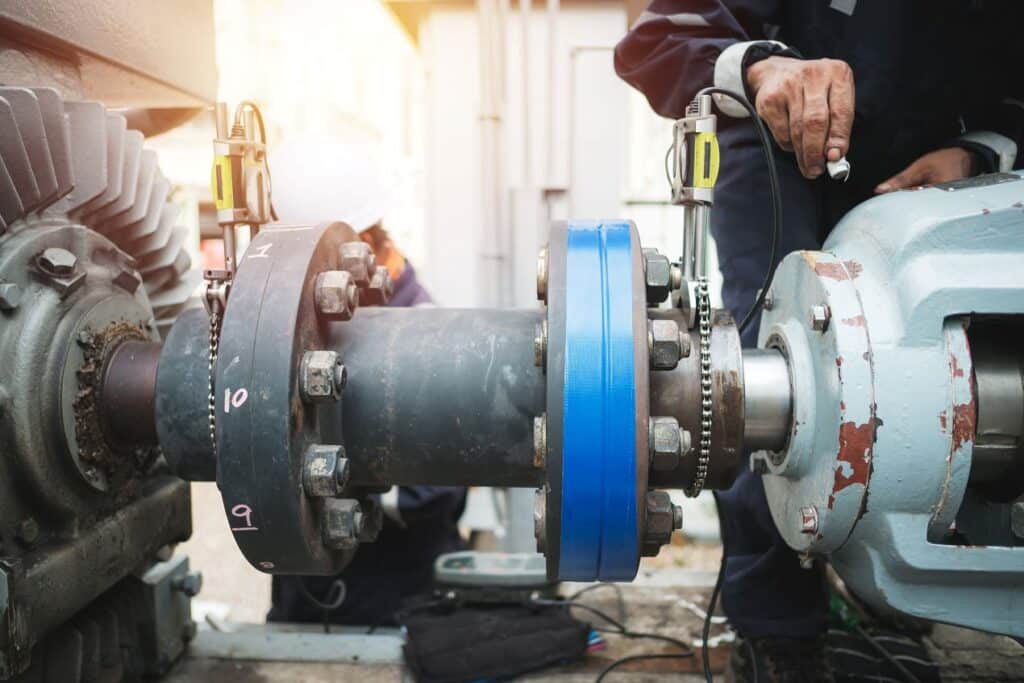 Close-up of hydrogen sensor inspection on industrial machinery with technician performing maintenance on bolted shaft assembly