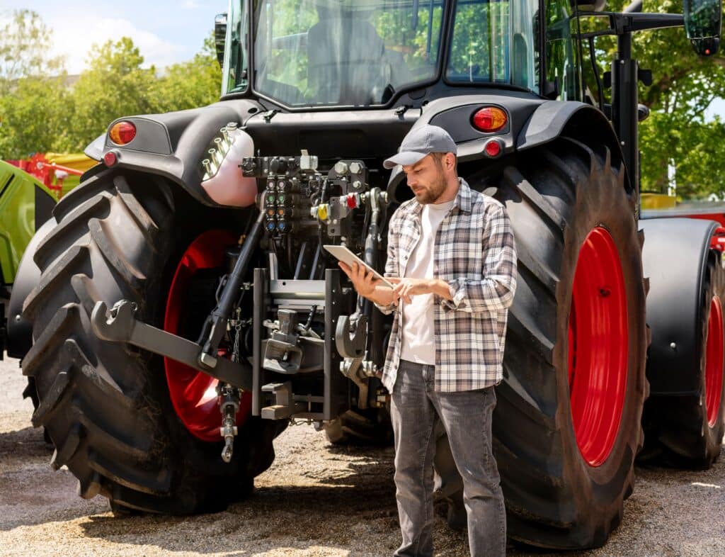 Landwirt mit Tablet prüft Traktor und Oberlenker