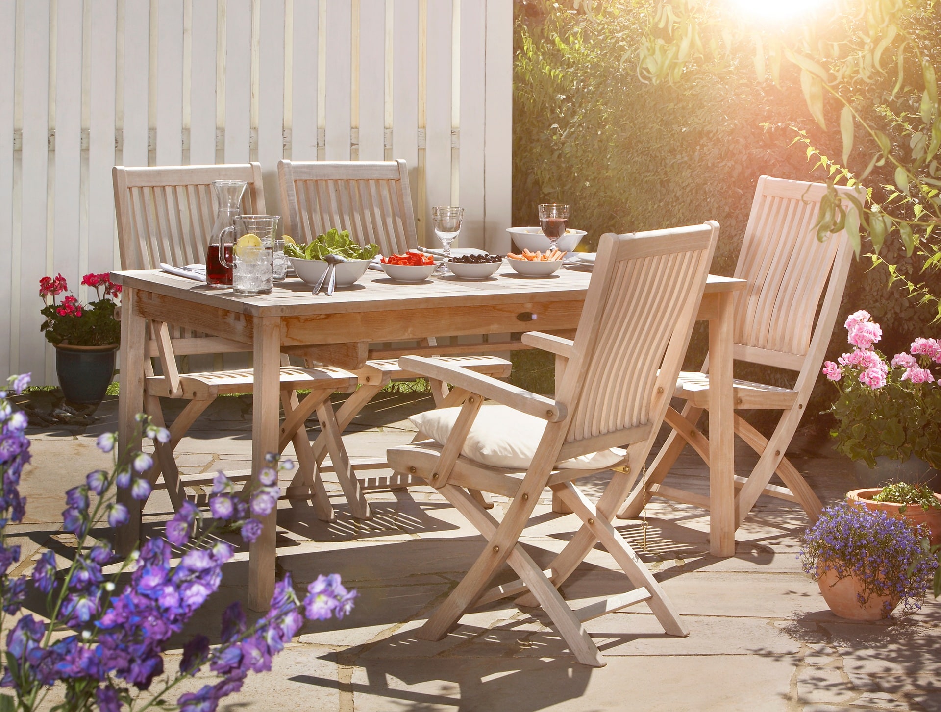 Holztisch mit Stühlen und Geschirr im Garten | Terrassenstühle